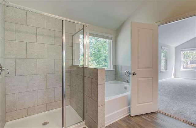 bathroom featuring hardwood / wood-style flooring, vaulted ceiling, and separate shower and tub