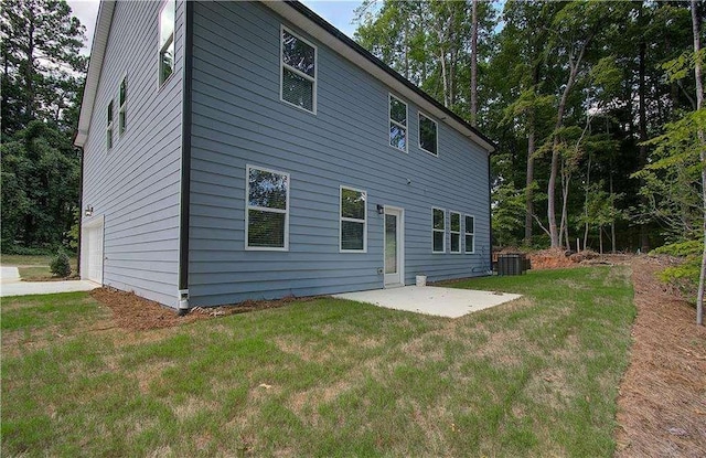 back of property featuring a garage, central air condition unit, a patio area, and a lawn