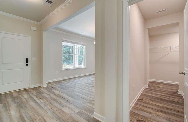 entrance foyer featuring ornamental molding and light hardwood / wood-style flooring