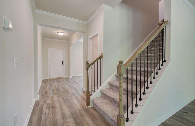 foyer with ornamental molding and light hardwood / wood-style floors