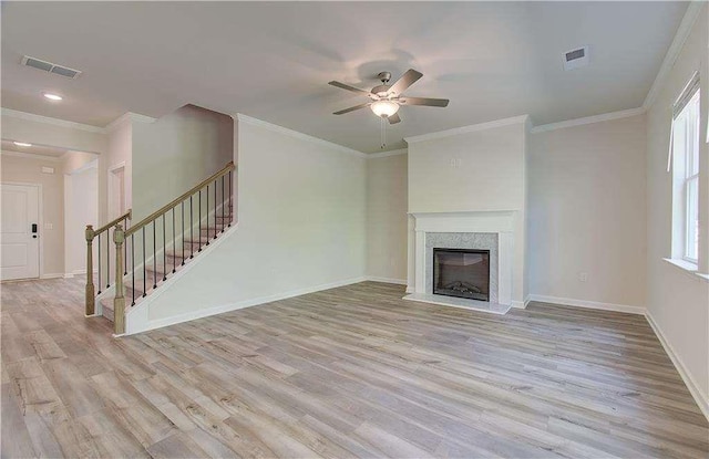 unfurnished living room featuring crown molding, a premium fireplace, and light hardwood / wood-style floors