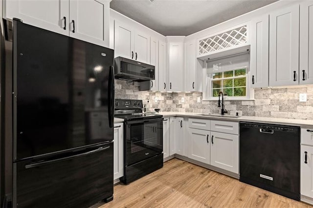 kitchen with white cabinets, light hardwood / wood-style floors, black appliances, and sink