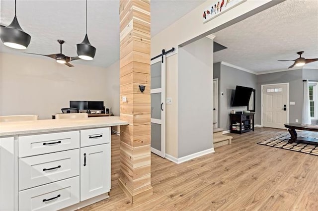 kitchen featuring light hardwood / wood-style flooring, hanging light fixtures, a barn door, white cabinets, and ceiling fan