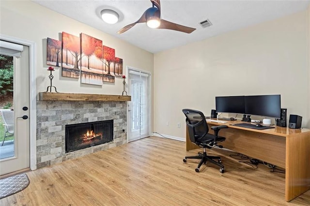 home office with ceiling fan, hardwood / wood-style floors, plenty of natural light, and a fireplace