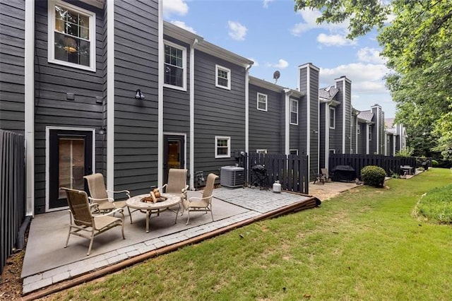 rear view of house with cooling unit, an outdoor fire pit, a patio area, and a lawn