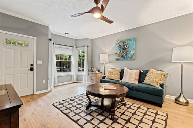 living room with a textured ceiling, ceiling fan, ornamental molding, and light hardwood / wood-style floors