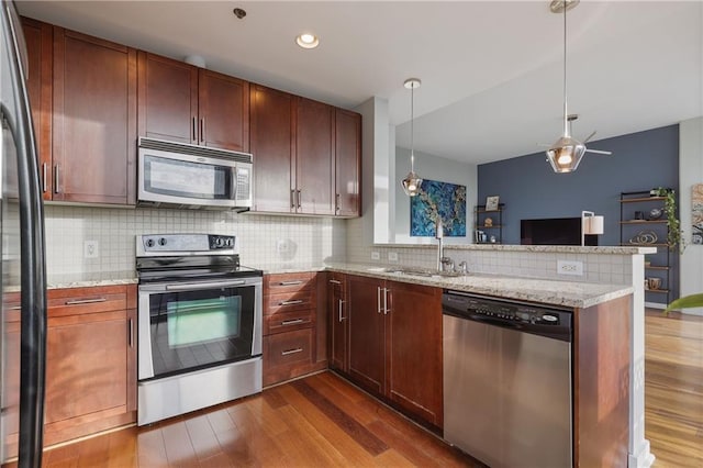 kitchen featuring tasteful backsplash, open floor plan, a peninsula, stainless steel appliances, and dark wood-style flooring