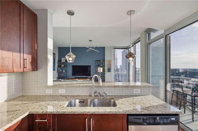 kitchen featuring dishwashing machine, light stone counters, a sink, open floor plan, and backsplash