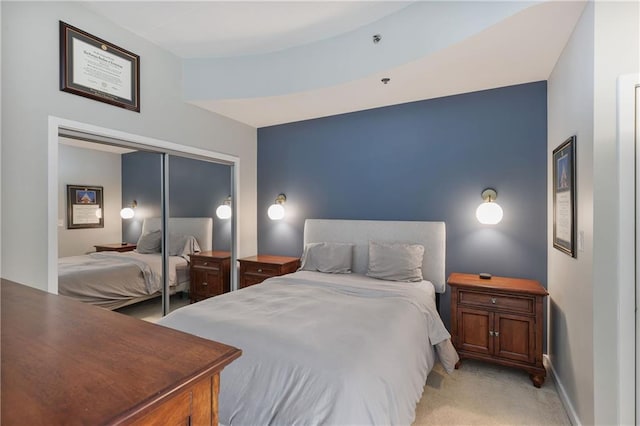 bedroom with a closet, light carpet, and baseboards