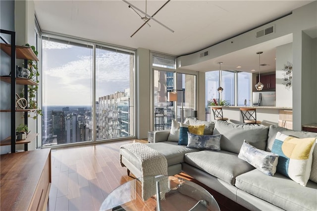 living area with visible vents, floor to ceiling windows, and wood finished floors