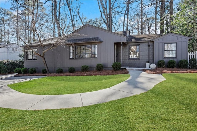 view of front facade featuring brick siding, board and batten siding, and a front yard