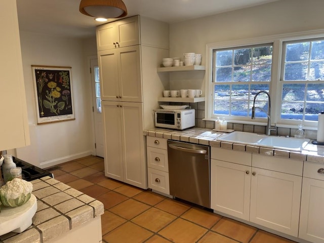 kitchen featuring white cabinetry, tile counters, stainless steel dishwasher, and sink