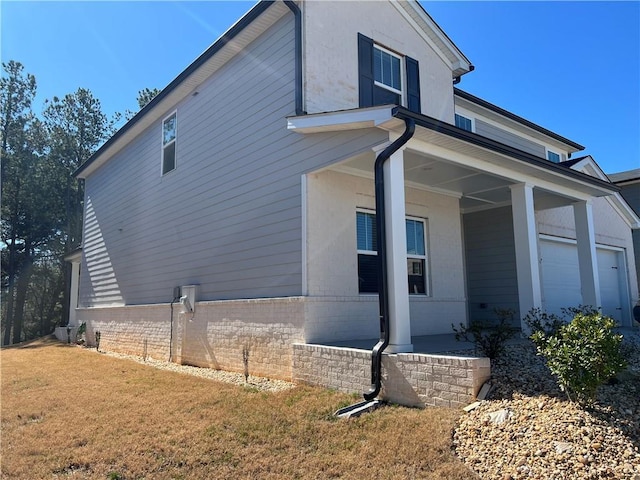 view of home's exterior with a garage, a yard, and brick siding