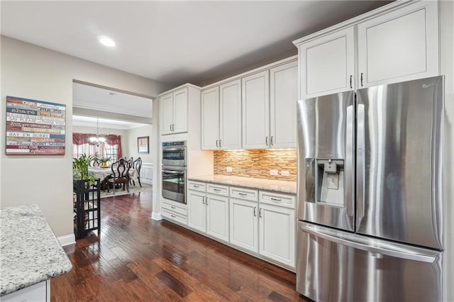 kitchen with dark wood finished floors, light stone counters, decorative backsplash, appliances with stainless steel finishes, and white cabinets