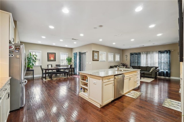 kitchen with dark wood finished floors, a center island with sink, open floor plan, and appliances with stainless steel finishes