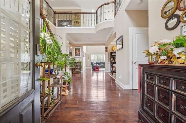 foyer entrance with baseboards, a high ceiling, dark wood finished floors, and crown molding