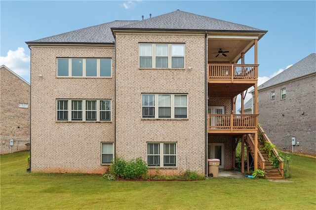 back of house with stairway, ceiling fan, a deck, a lawn, and brick siding