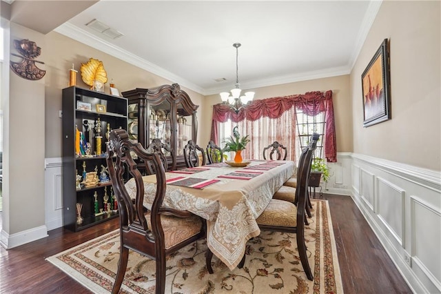 dining room with visible vents, a wainscoted wall, ornamental molding, an inviting chandelier, and wood finished floors