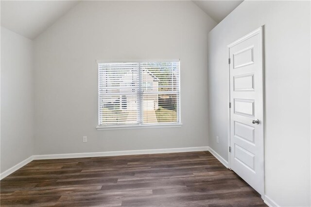 spare room with dark wood-type flooring and vaulted ceiling
