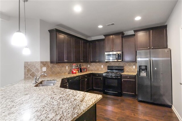 kitchen with black appliances, sink, hanging light fixtures, light stone countertops, and dark hardwood / wood-style flooring