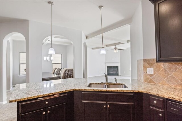 kitchen with backsplash, sink, dark brown cabinets, beam ceiling, and kitchen peninsula