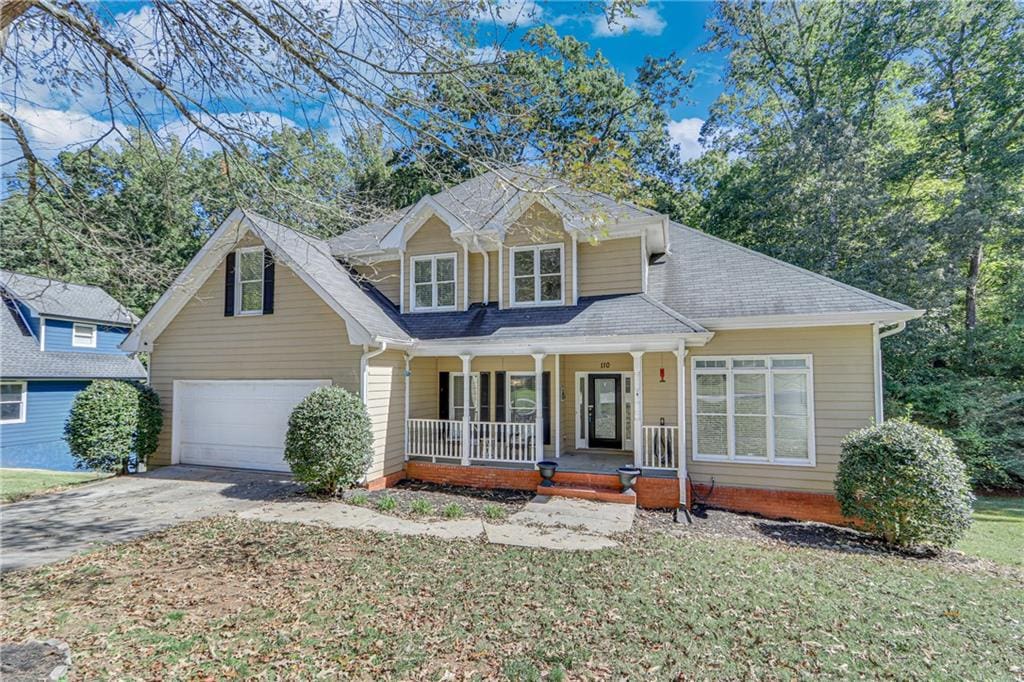 view of front of home with a porch, a garage, and a front lawn