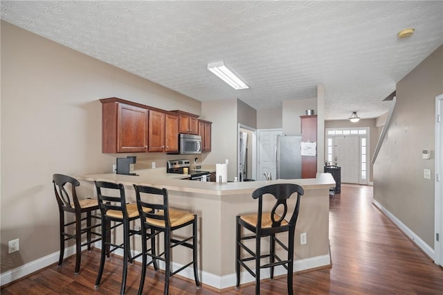 40 Brickton Way E, Dawsonville, GA 30534 - kitchen with appliances with stainless steel finishes, a peninsula, brown cabinetry, dark wood-style floors, and light countertops