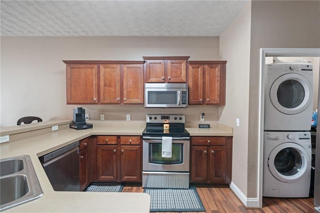 40 Brickton Way E, Dawsonville, GA 30534 - kitchen with appliances with stainless steel finishes, stacked washer and clothes dryer, wood finished floors, a peninsula, and light countertops