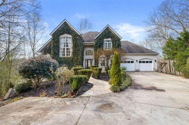 traditional-style home featuring an attached garage, concrete driveway, and stucco siding