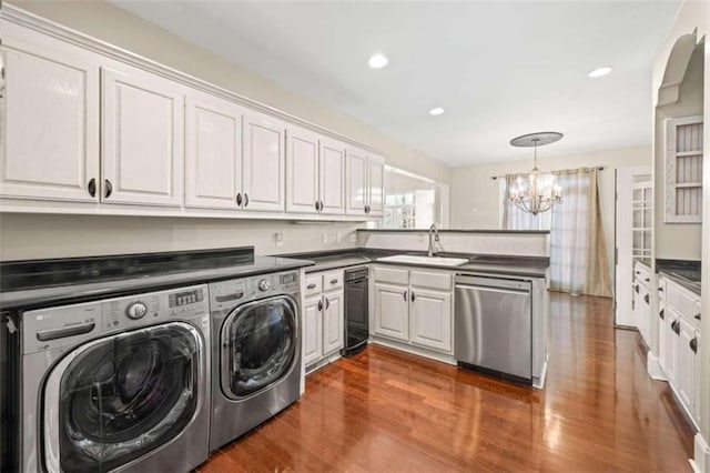 clothes washing area featuring sink, washer and dryer, dark hardwood / wood-style floors, and a notable chandelier