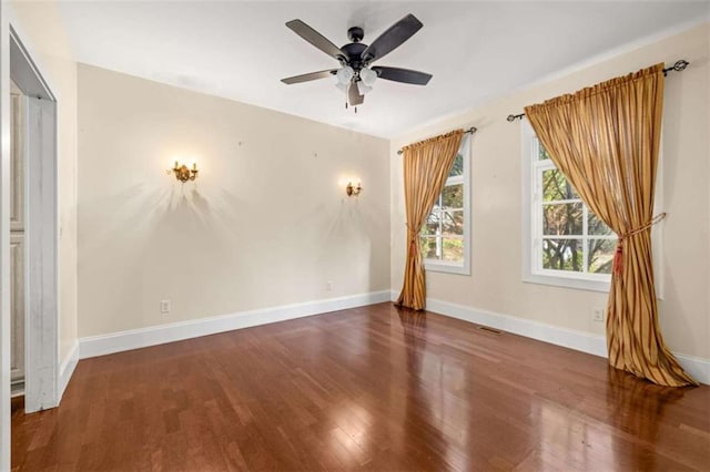 empty room with visible vents, ceiling fan, wood finished floors, and baseboards