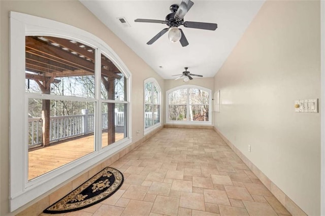 unfurnished sunroom featuring visible vents, baseboards, stone tile flooring, and lofted ceiling