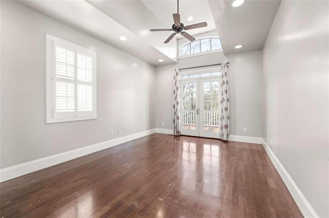 unfurnished room featuring a towering ceiling, french doors, dark hardwood / wood-style flooring, and ceiling fan