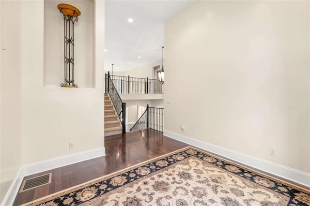 empty room featuring stairway, visible vents, baseboards, and wood finished floors