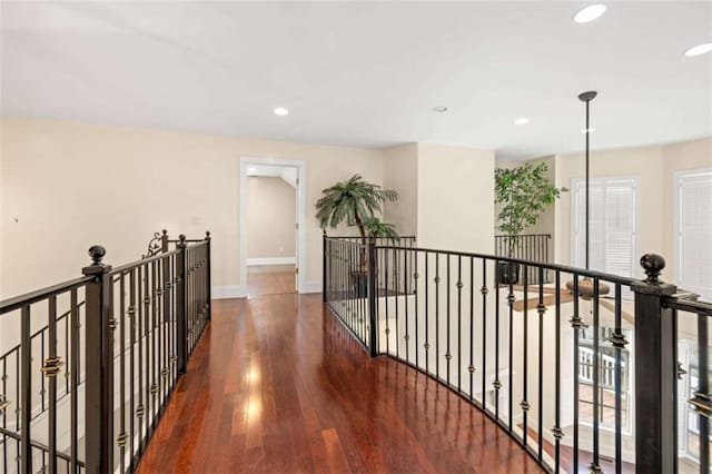 hallway with wood finished floors, baseboards, an upstairs landing, and recessed lighting