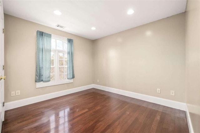 empty room featuring wood finished floors, baseboards, visible vents, and recessed lighting