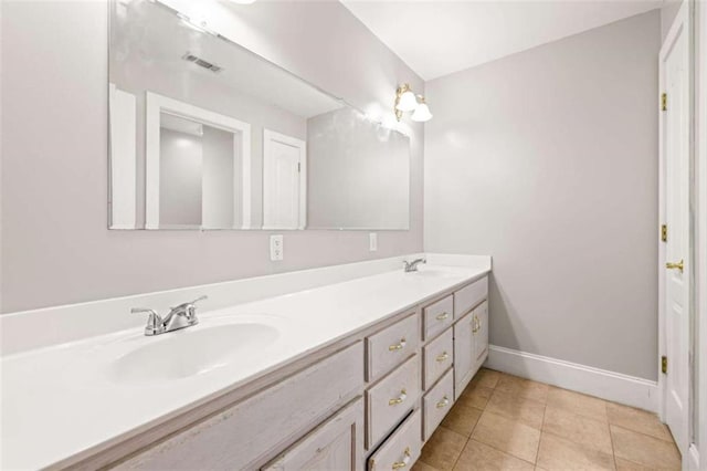 bathroom with tile patterned floors, double vanity, baseboards, and a sink