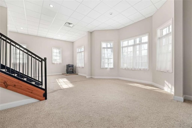 interior space featuring carpet, a wood stove, and a drop ceiling