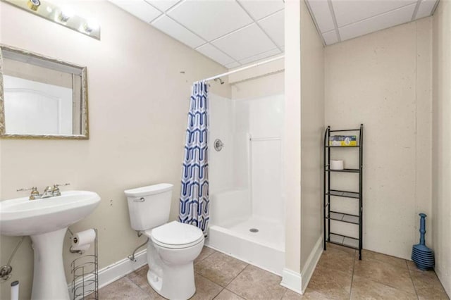 bathroom with toilet, tile patterned floors, a shower stall, and a drop ceiling