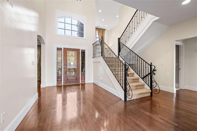 foyer entrance with a towering ceiling and dark hardwood / wood-style floors