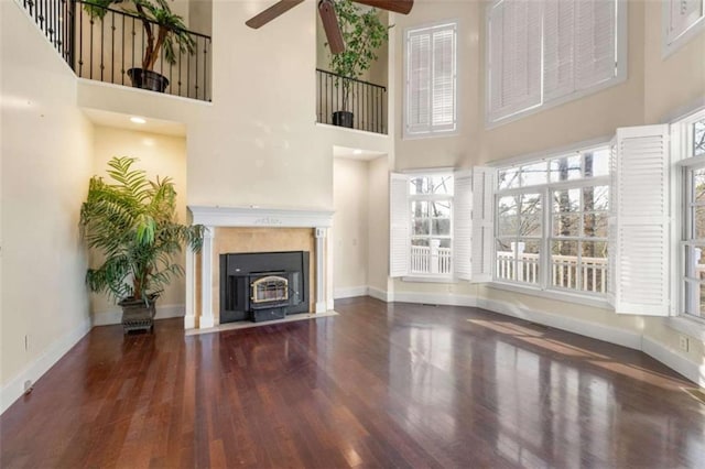 unfurnished living room with ceiling fan, a healthy amount of sunlight, dark hardwood / wood-style flooring, and a towering ceiling