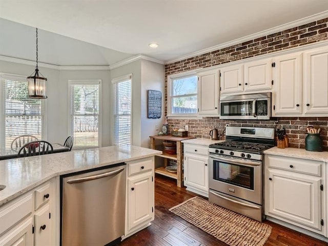 kitchen featuring white cabinets, stainless steel appliances, and brick wall