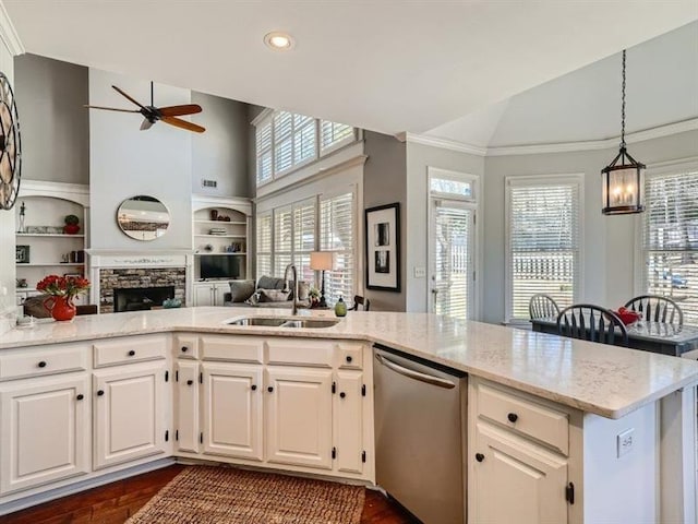 kitchen featuring dishwasher, white cabinets, sink, built in shelves, and a fireplace