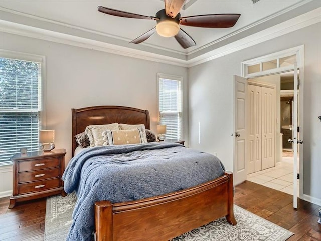 bedroom with a closet, ceiling fan, crown molding, and hardwood / wood-style floors