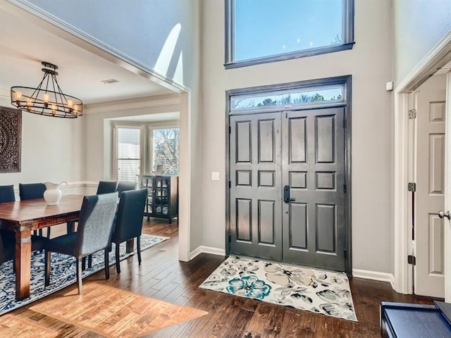 foyer featuring dark hardwood / wood-style floors, an inviting chandelier, and ornamental molding