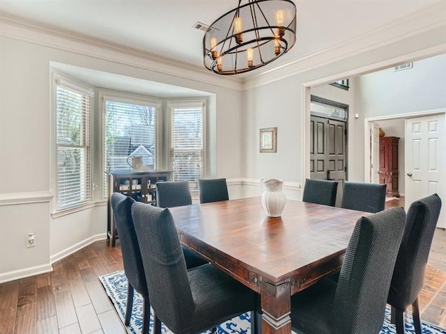 dining space with hardwood / wood-style floors, crown molding, and a notable chandelier