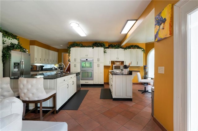 790 Friendship Church Rd, Douglasville, GA 30134 - kitchen featuring a center island with sink, stainless steel appliances, dark countertops, dark tile patterned floors, and a kitchen breakfast bar