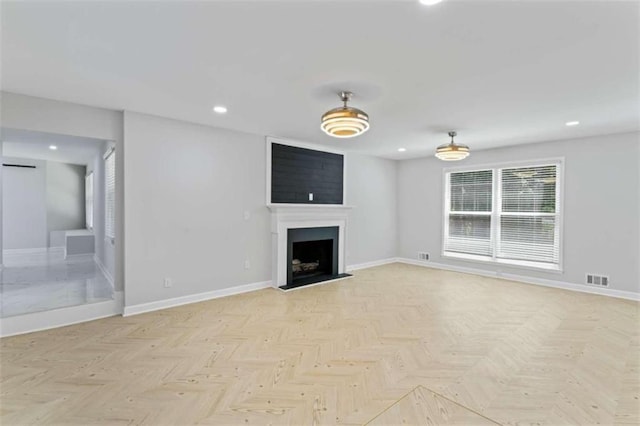 unfurnished living room featuring recessed lighting, baseboards, visible vents, and a fireplace with raised hearth