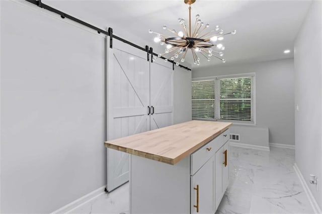 kitchen featuring a barn door, visible vents, marble finish floor, and wooden counters