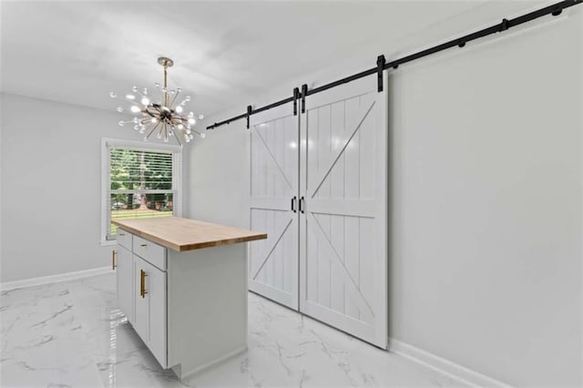 kitchen with a notable chandelier, marble finish floor, wood counters, a barn door, and baseboards